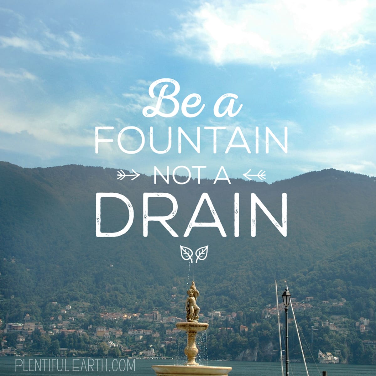 Be a fountain, not a drain" superimposed over a scenic view of a body of water with a witchy fountain in the foreground and mountains in the distance.