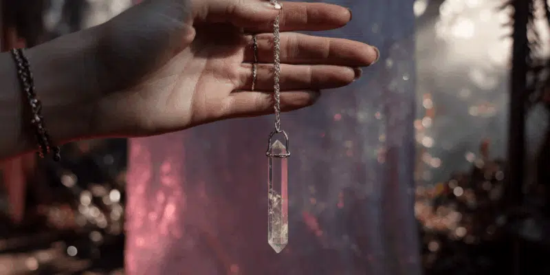 a hand holding a crystal pendulum to practice how to use a pendulum