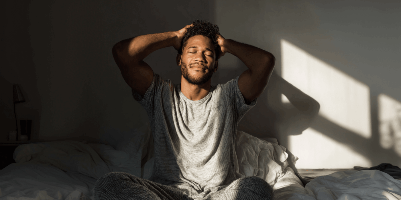 a man sitting on a bed with his eyes closed