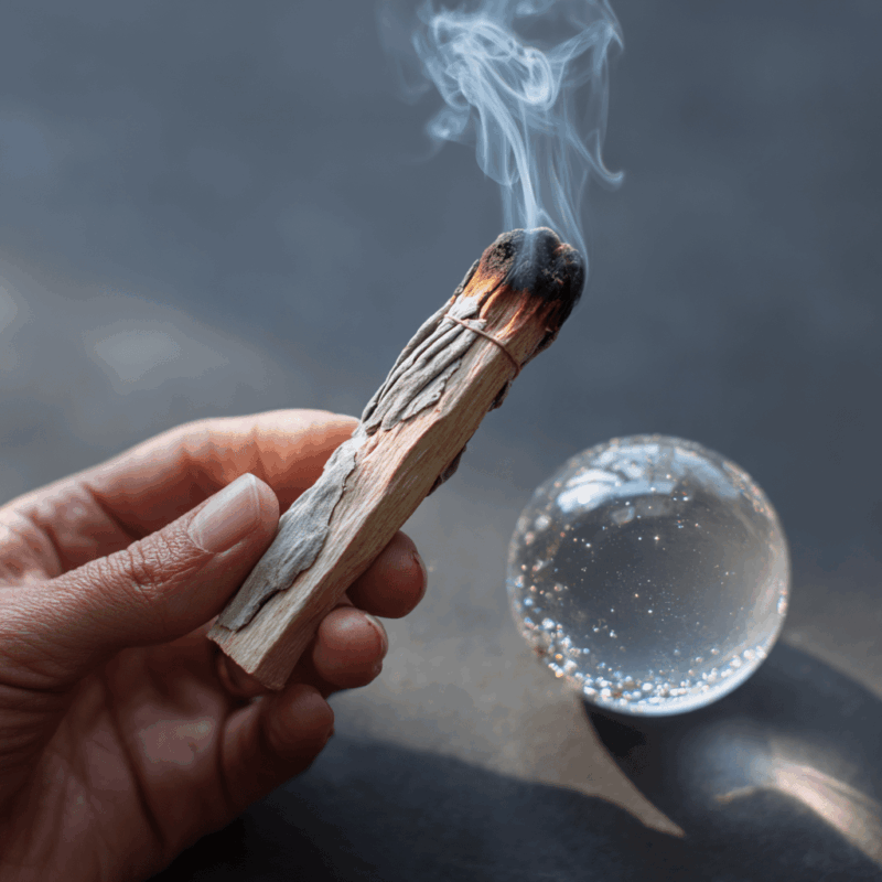 How To Cleanse Your Crystal Ball: Simple Steps Tor Spiritual Clarity 2 a hand holding a stick with smoke coming out of it. Cleansing a crystal ball.