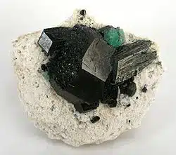 Tourmaline vs. Onyx: The Key Differences Between These Protective Crystals 2 Black and green mineral cluster on rock. This is tourmaline. black tourmaline vs black onyx