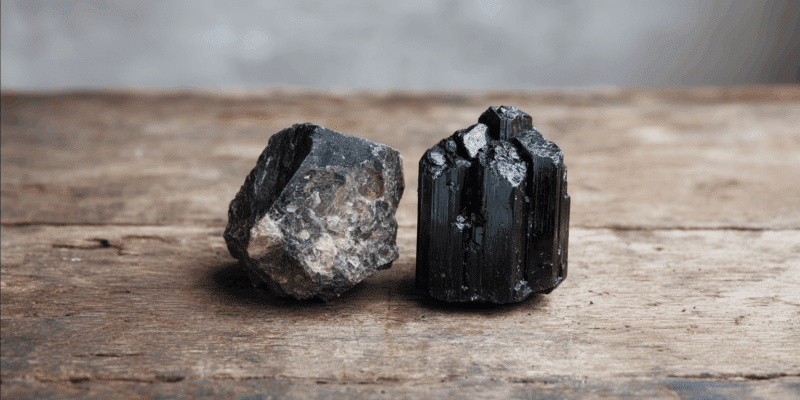 Two black mineral specimens on wood