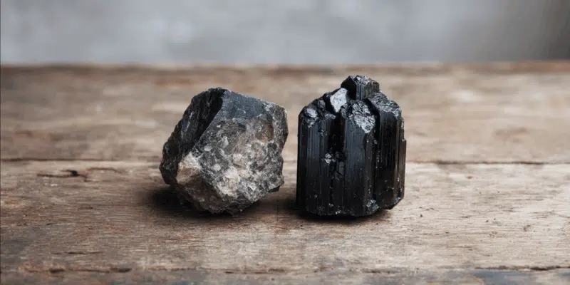 Two black mineral specimens on wood