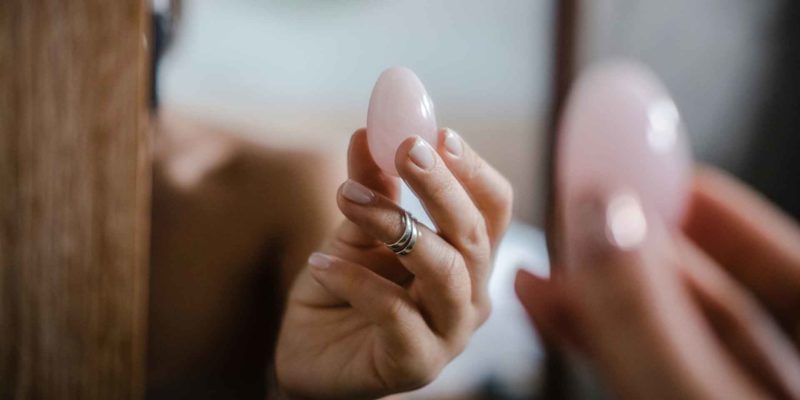 Yoni Eggs: Dangerous? Your Ultimate Guide 2 A witchy person applying makeup with a sponge, focusing on the details in the mirror.