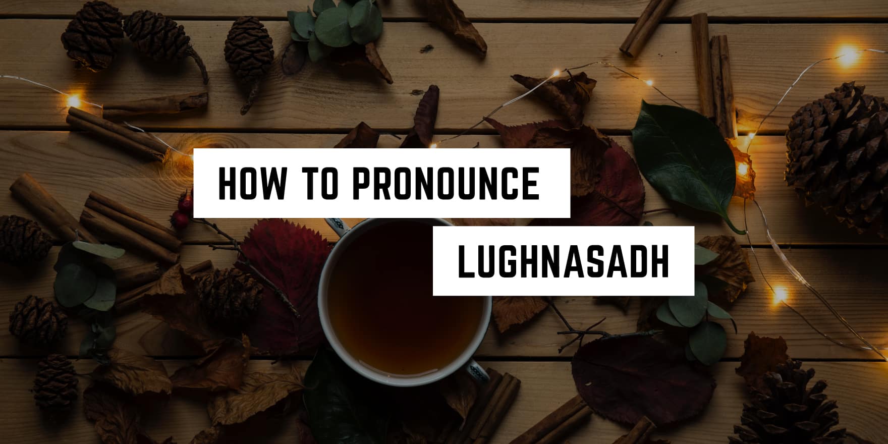 Autumn ambiance with a witchy tutorial: "how to pronounce lughnasadh" surrounded by pine cones, autumn leaves, a cup of tea, and twinkling string lights on a wooden surface