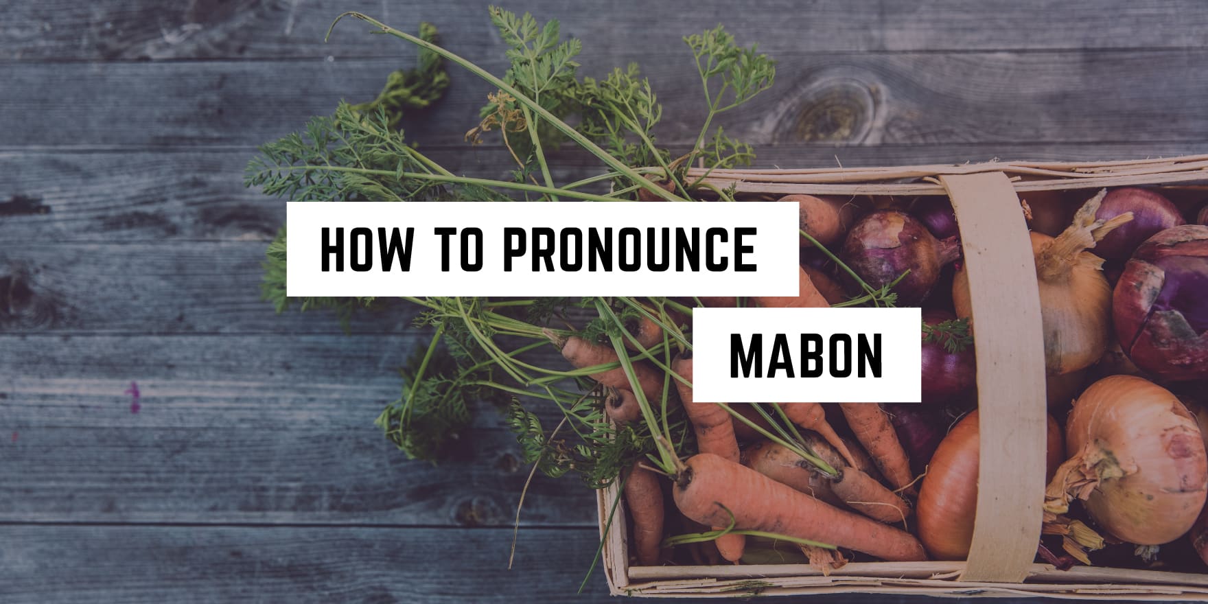 A rustic crate filled with an assortment of fresh garden vegetables, including carrots and onions, with a superimposed text that reads: "how to pronounce Mabon," perfect for any metaphysical shop