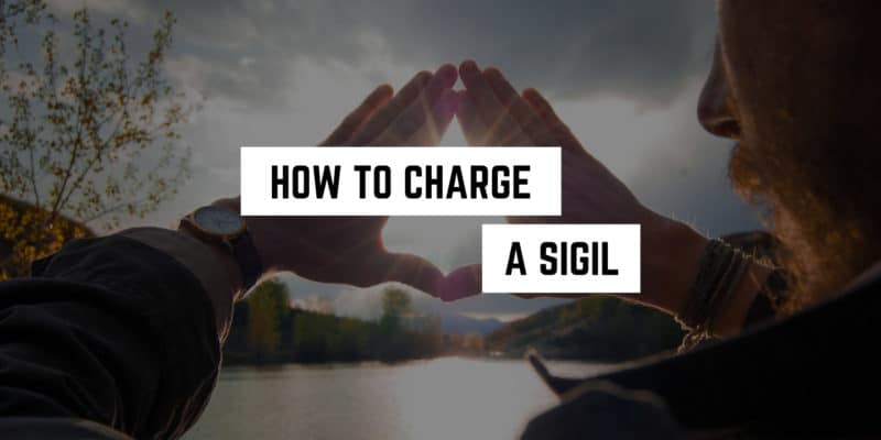 How Do You Charge a Sigil? 8 A person holding their hands up to frame a natural scene with text overlay that reads "how to charge a sigil" in front of a metaphysical shop.