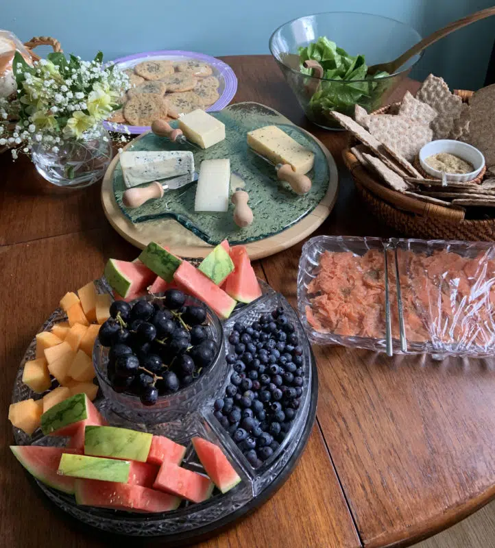 Midsummer: The Reawakening of a Witch 4 A table filled with cheeses, fruits, crackers, salad, and lavender cookies.