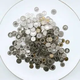 A collection of assorted coins spread out on a white surface within a circular boundary, selected from the offerings of a metaphysical shop.