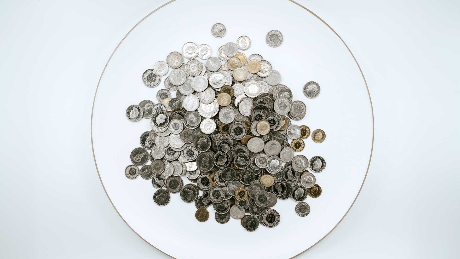 A collection of assorted coins spread out on a white surface within a circular boundary, selected from the offerings of a metaphysical shop.
