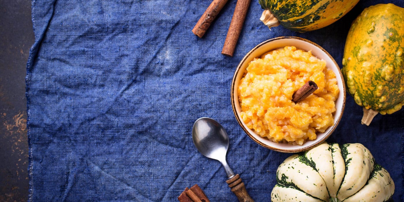 pumpkin applesauce in a bowl on a blue table with pumpkins around it