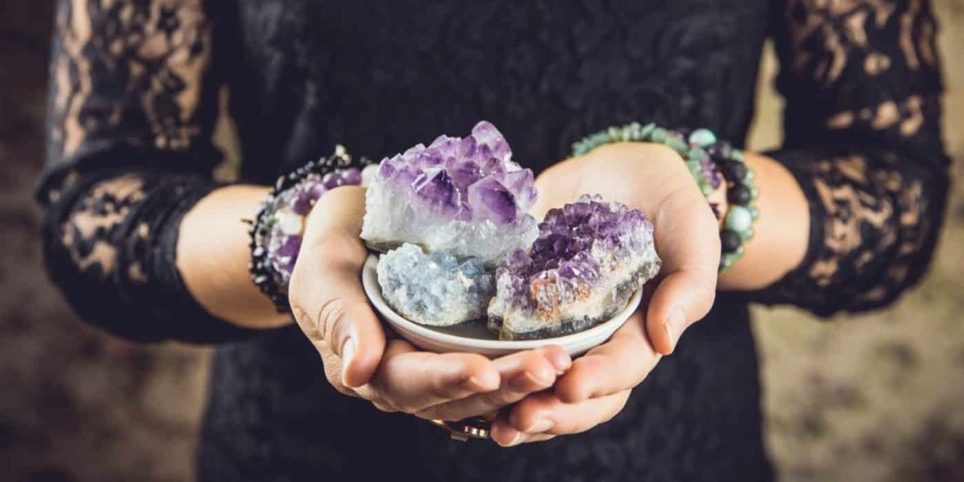 A woman in black holding three amethyst geode clusters