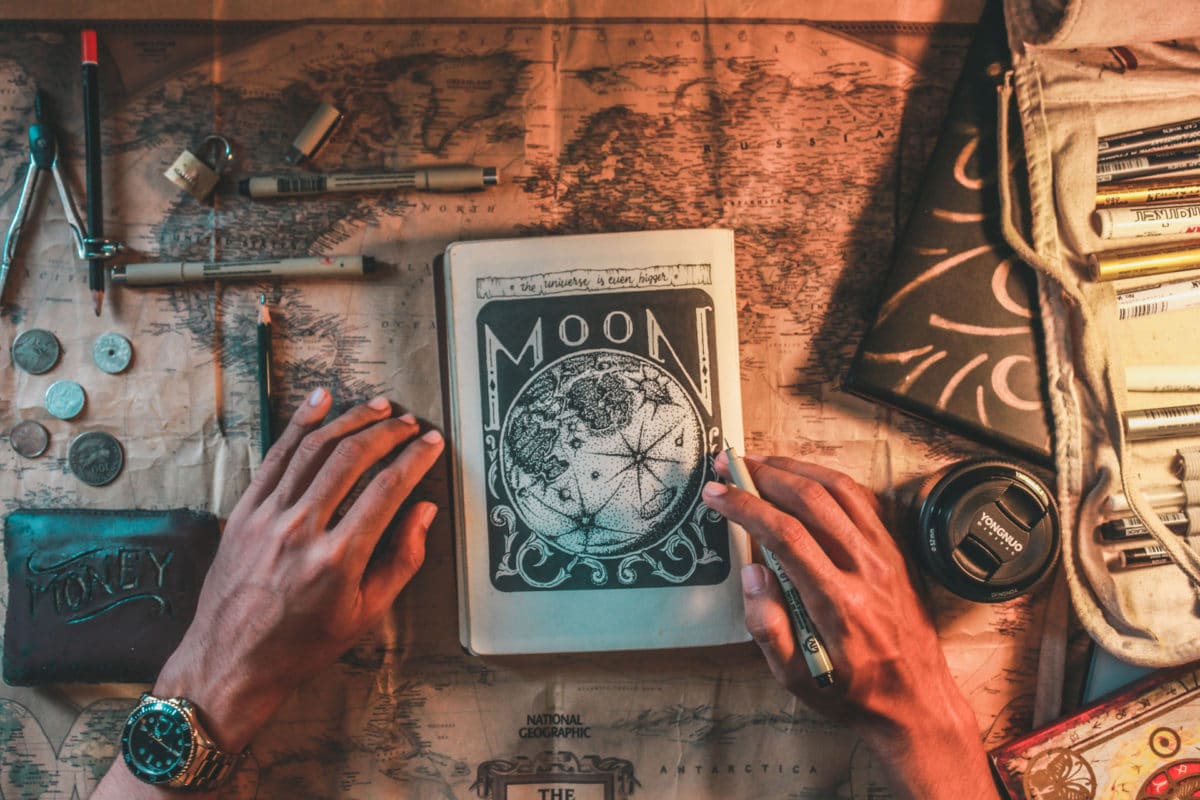 two hands holding a moon book on a wooden table