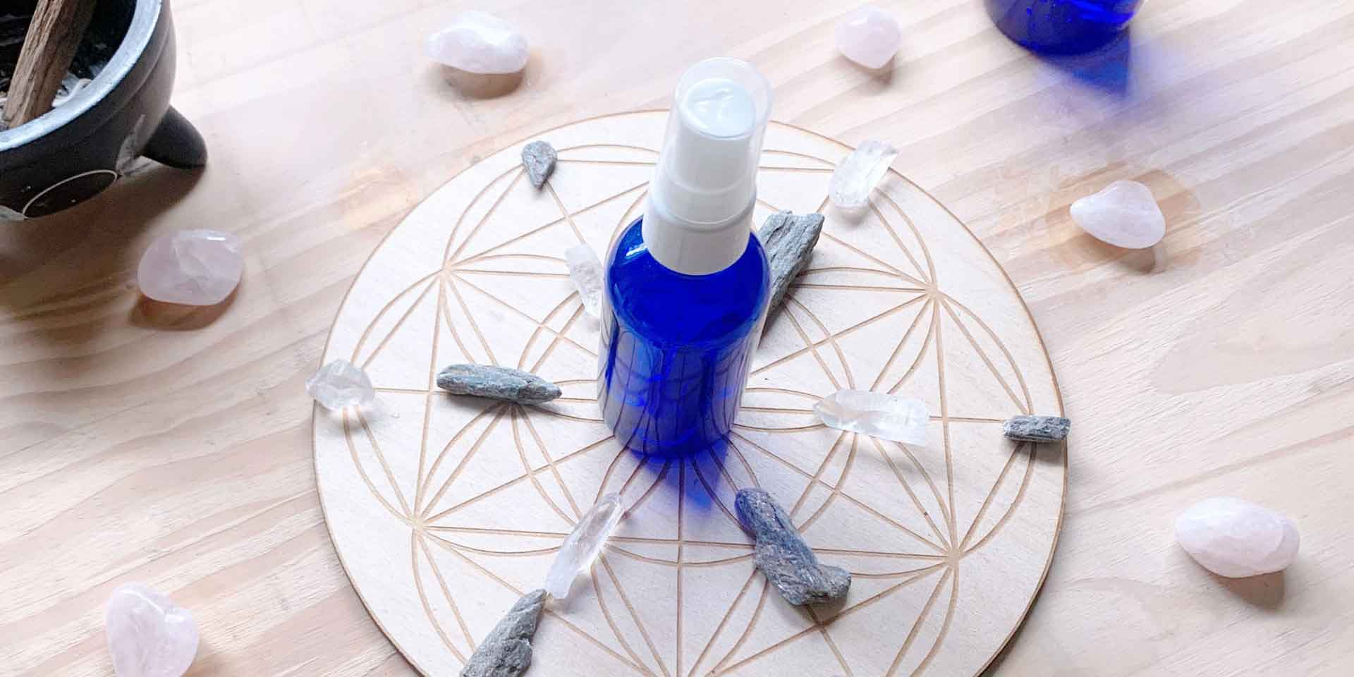 A bottle of essential oil spray on a wooden table with a geometric pattern, surrounded by an array of crystal stones, evoking a sense of tranquility and metaphysical wellness.