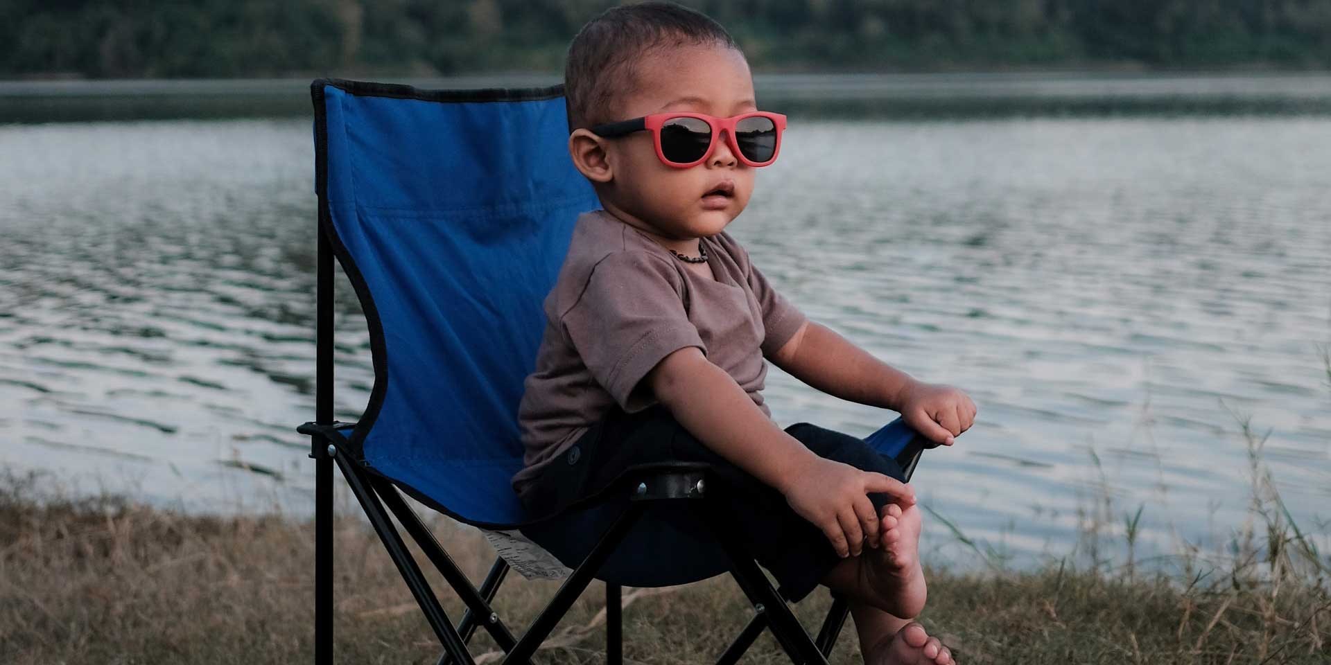 Little trendsetter chilling by the lakeside in stylish red sunglasses and a witchy vibe.
