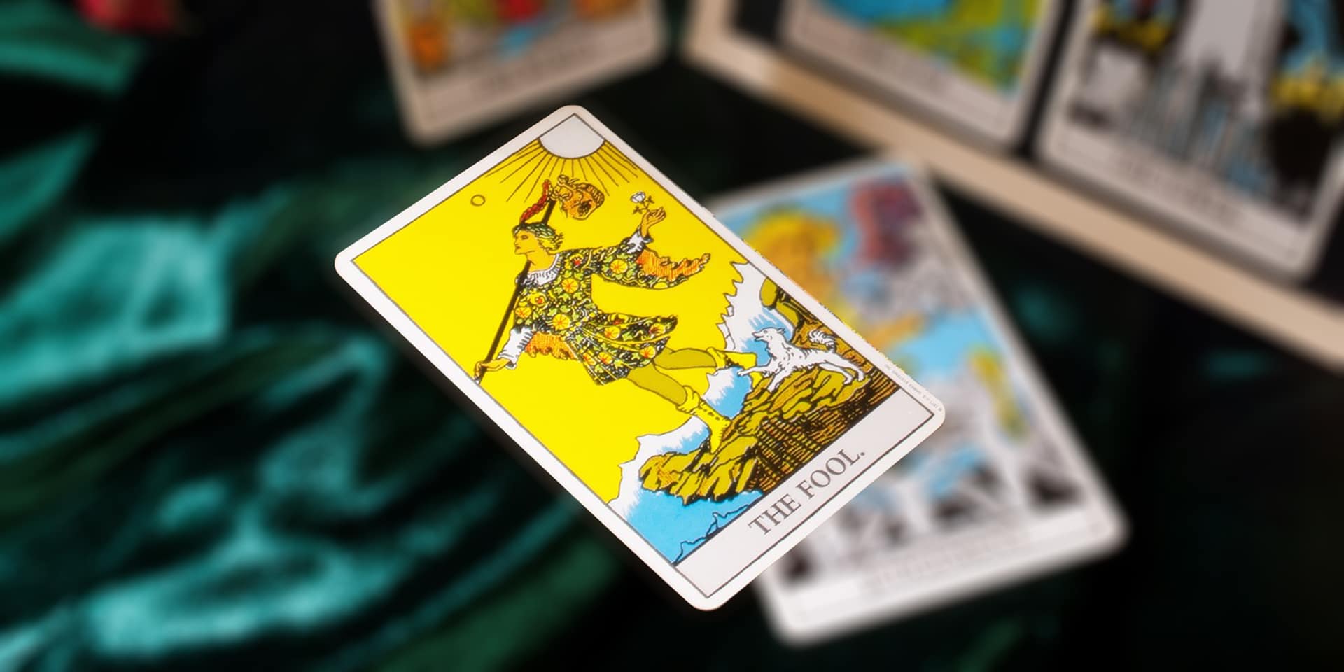 A metaphysical tarot card named "the fool" prominently displayed in focus, with other blurred cards in the background, suggestive of a tarot reading in progress.