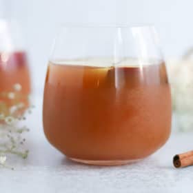 Instant Pot Apple Cider Recipe 10 Two glasses of iced tea with a hint of cinnamon, accompanied by delicate white flowers, offering a refreshing moment on a serene backdrop infused with metaphysical energy.