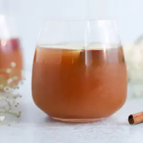 Two glasses of iced tea with a hint of cinnamon, accompanied by delicate white flowers, offering a refreshing moment on a serene backdrop infused with metaphysical energy.