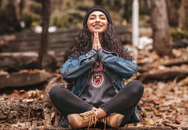 A woman meditating outside in autumn leaves