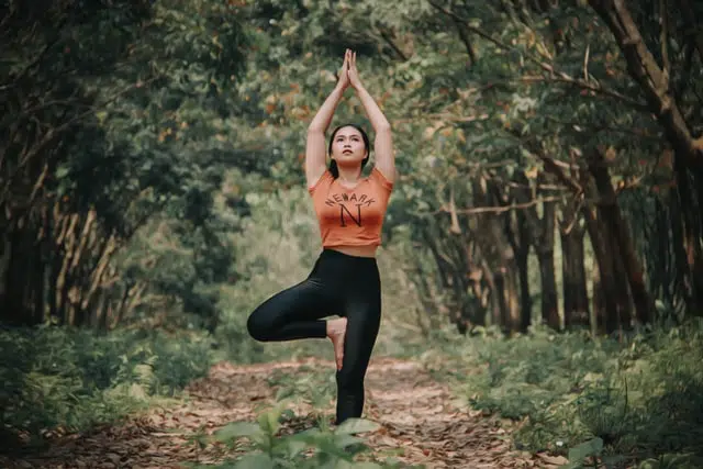 A person practicing yoga in a tranquil forest, finding balance and spiritual peace amidst nature.