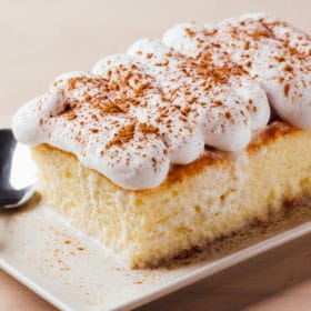 a rectangular shaped cake with white whipped cream and cinnamon on top
