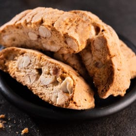 Tasty sweet biscotti cookies with nuts and almonds on old black background. italian dessert snack.