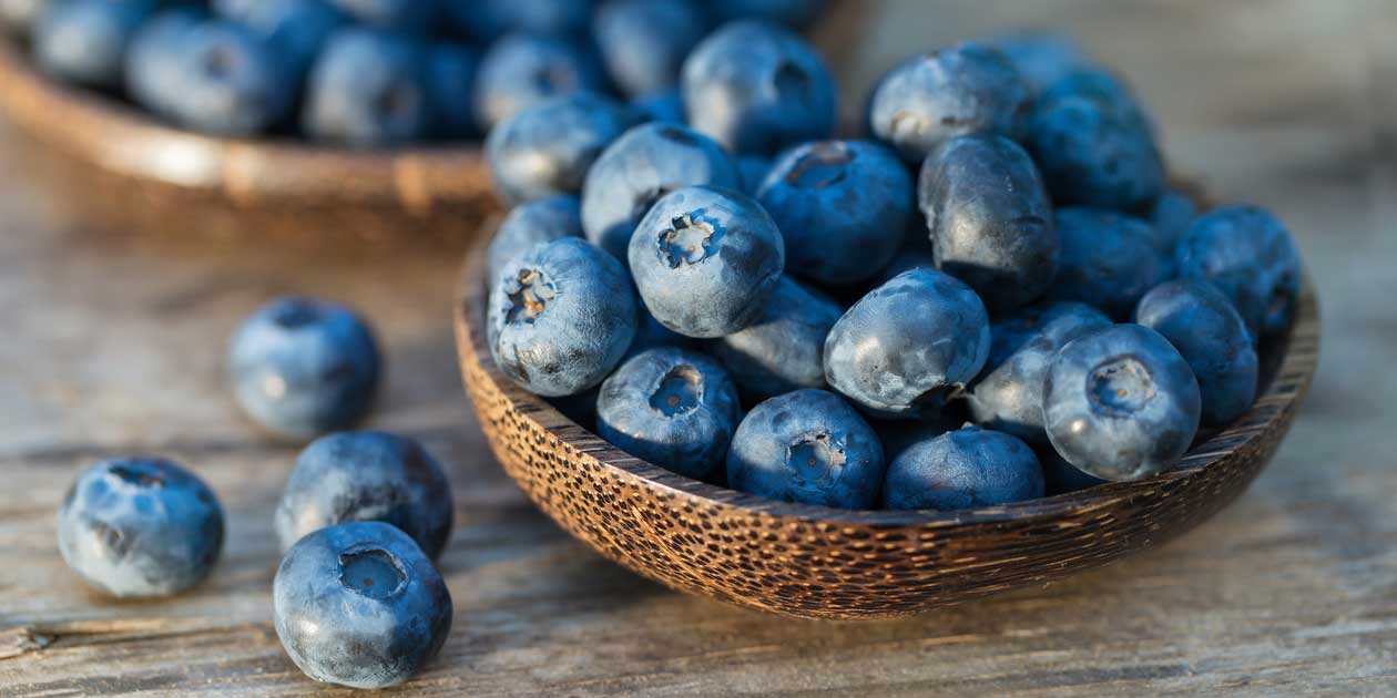 A bowl full of ripe blueberries sitting on a rustic wooden surface, exuding a spiritual ambiance.