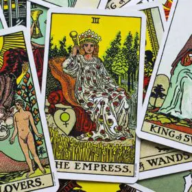 A vibrant collection of tarot cards, a new age product, spread out, with "the empress" card drawing focus amidst various other richly illustrated symbols and figures.