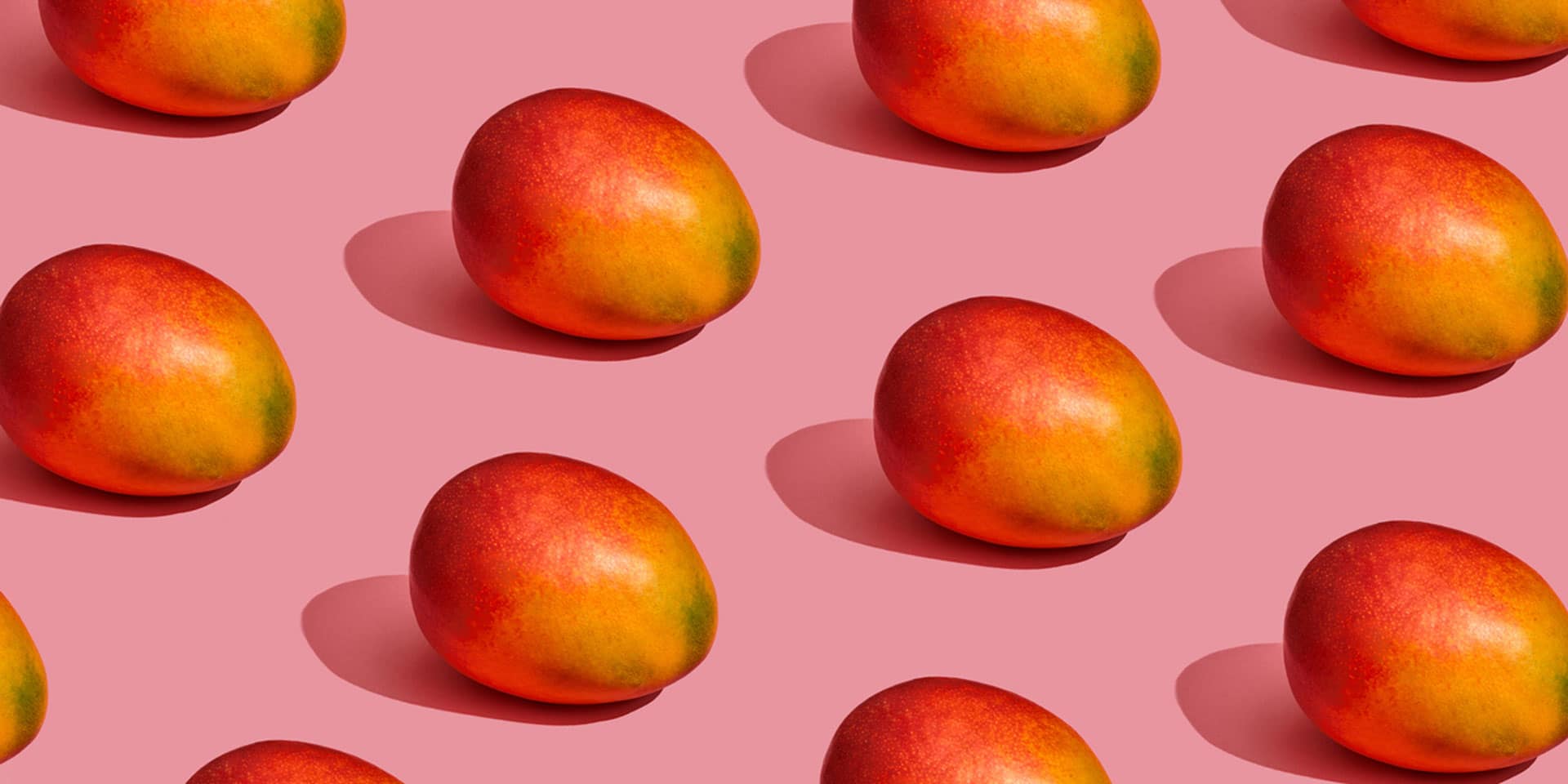 A pattern of ripe, colorful mangoes against a uniform pink background, symbolizing a new age spiritual journey.
