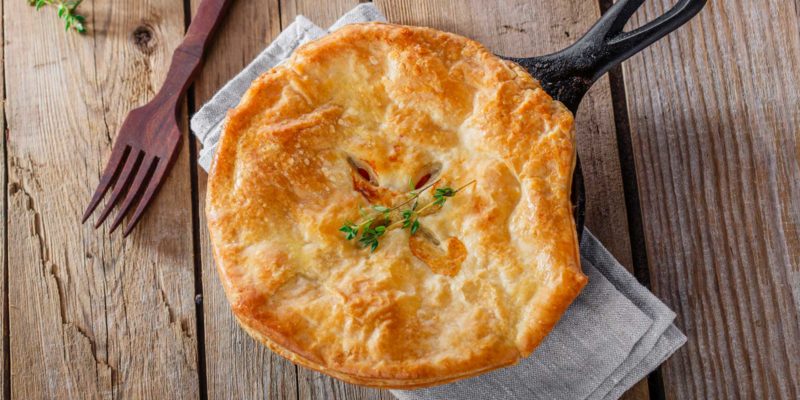 Vegetarian Pot Pie for Beauty, Grounding, and Protection 18 Golden pot pie fresh from the oven, served in a cast-iron skillet on a rustic wooden table, hinting at a metaphysical comfort meal.