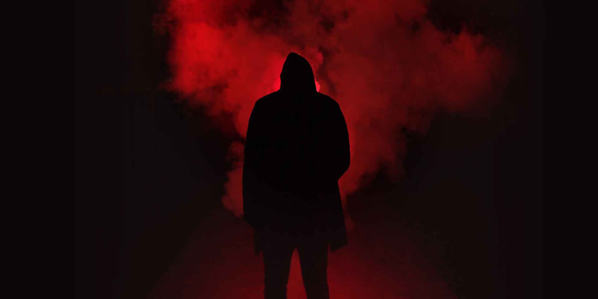 A silhouette of a person stands shrouded in mystery amidst a deep red haze, evoking a sense of metaphysical intrigue and suspense.