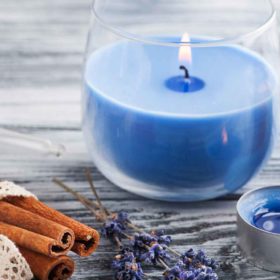 Blue Candle Meanings For Spells | Candle Magic 18 Two blue candles on a wooden table, surrounded by dried lavender, cinnamon sticks, and an essential oil bottle