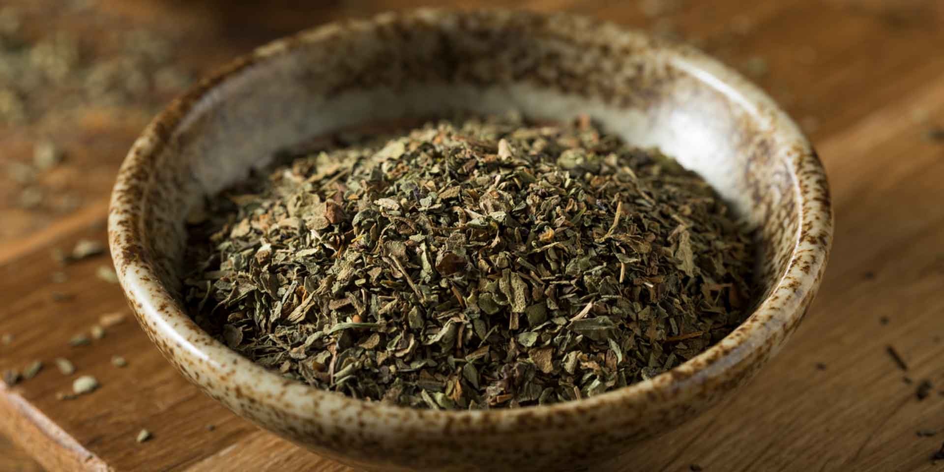 A bowl of dried herbs on a wooden table