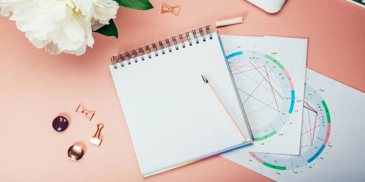 Take The 6-Day #StationsDirectChallenge: Find Out How Mercury Retrogrades & More Make Your Life Better 1 a notebook on astrological charts on a pink table