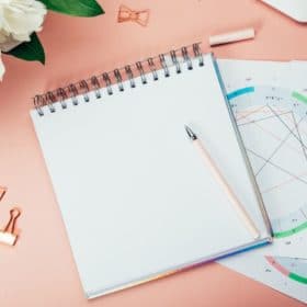 a notebook on astrological charts on a pink table