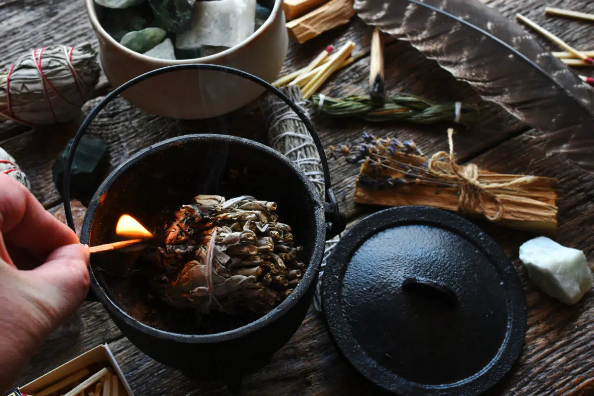 burning herbs in a cauldron with a match