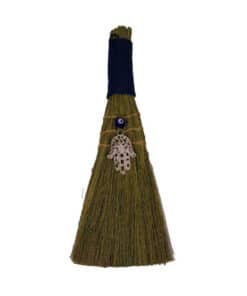 A brown, natural twig hand broom with a nazar and hamsa to ward off harmful energies.
