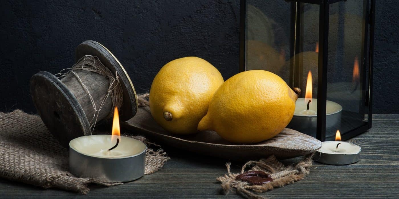 A table with lemons on it and a white candle for a magical spell