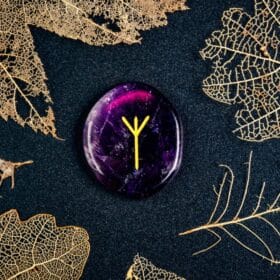 Algiz Rune: History & How To Unlock Its Protective Power 33 A purple crystal with a golden algiz drawn on it, surrounded by golden leaves