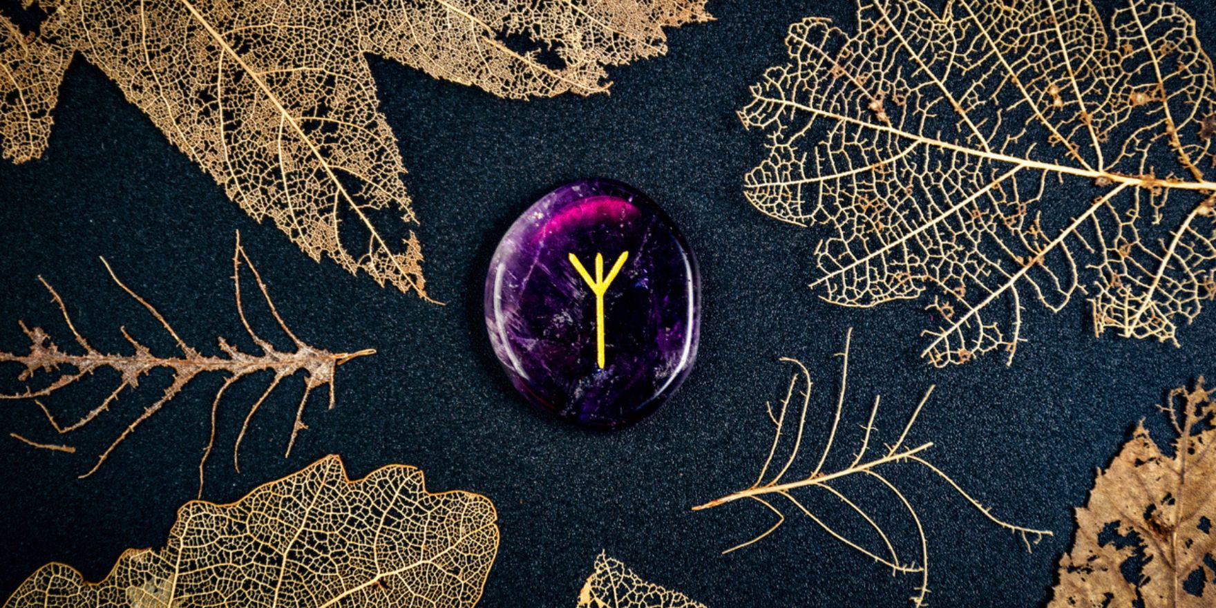 A purple crystal with a golden algiz drawn on it, surrounded by golden leaves