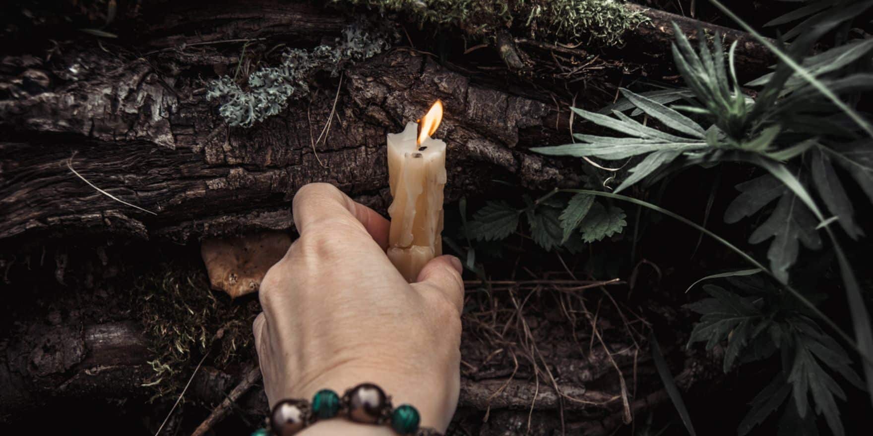A woman placing a natural candle at the base of a tree