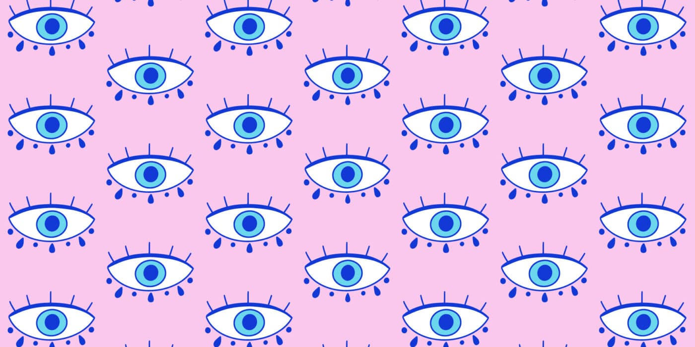 A pink background with repetitive blue evil eye illustrations in a pattern