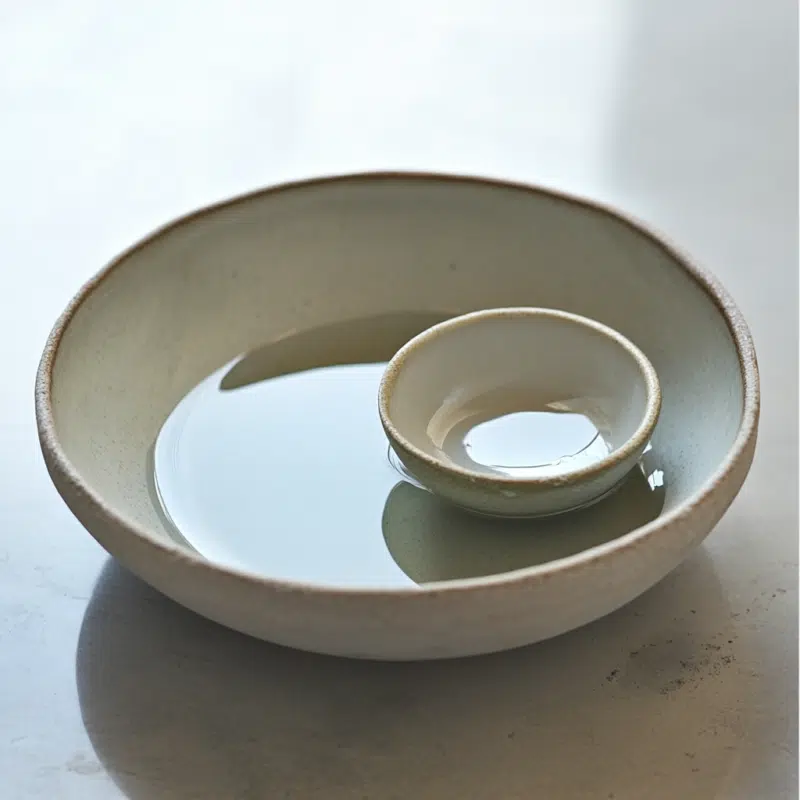 9 Powerful Ways to Use Whole High John the Conqueror Root in Your Spiritual Practice 4 Two ceramic bowls, one inside the other, with water in the larger bowl. The inner bowl remains dry, used for preparing an indirect crystal elixir safely.