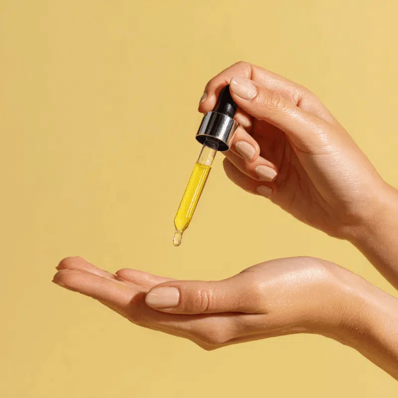 Hands holding dropper with body oil recipe