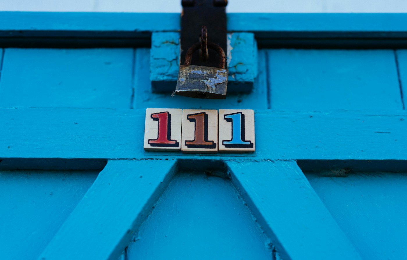 Three painted number ones, red, brown, and blue, on a bright blue wooden door