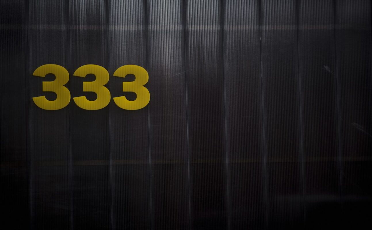 The number 333 in gold metal numerals on a dark ribbed wall