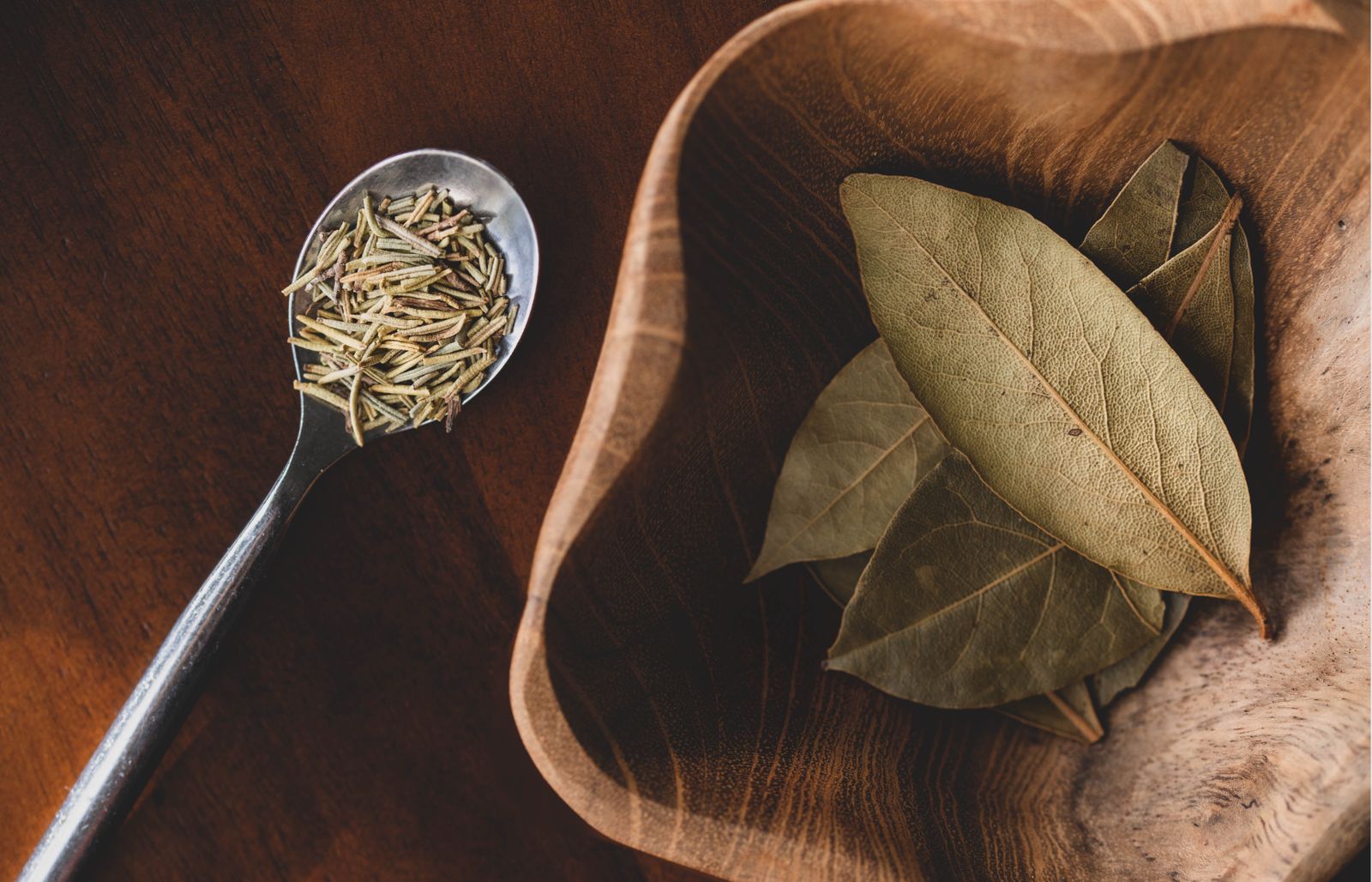 Bay leaves and dried rosemary for protection spells Plentiful Earth | Global Spirituality Dried bay leaves in a wooden bowl beside a spoon of dried rosemary