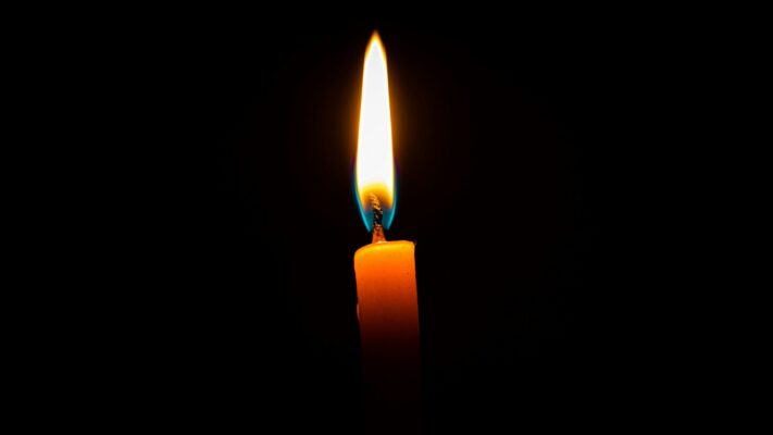 candleflamemeaning Plentiful Earth | Global Spirituality A single orange candle burning in the dark, with a blue base at the wick and a tall, steady yellow-white flame.