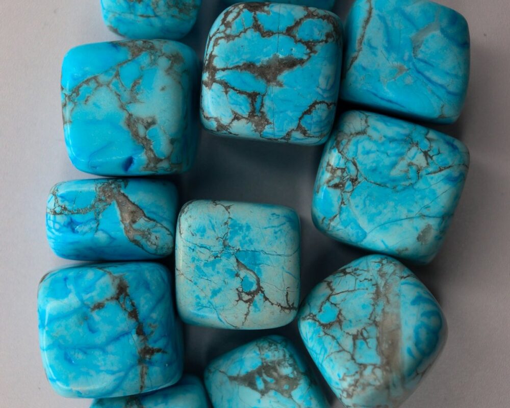 Bright blue tumbled stones with gray veins, darker blue dye pooled in their cracks, and pale chalky patches.