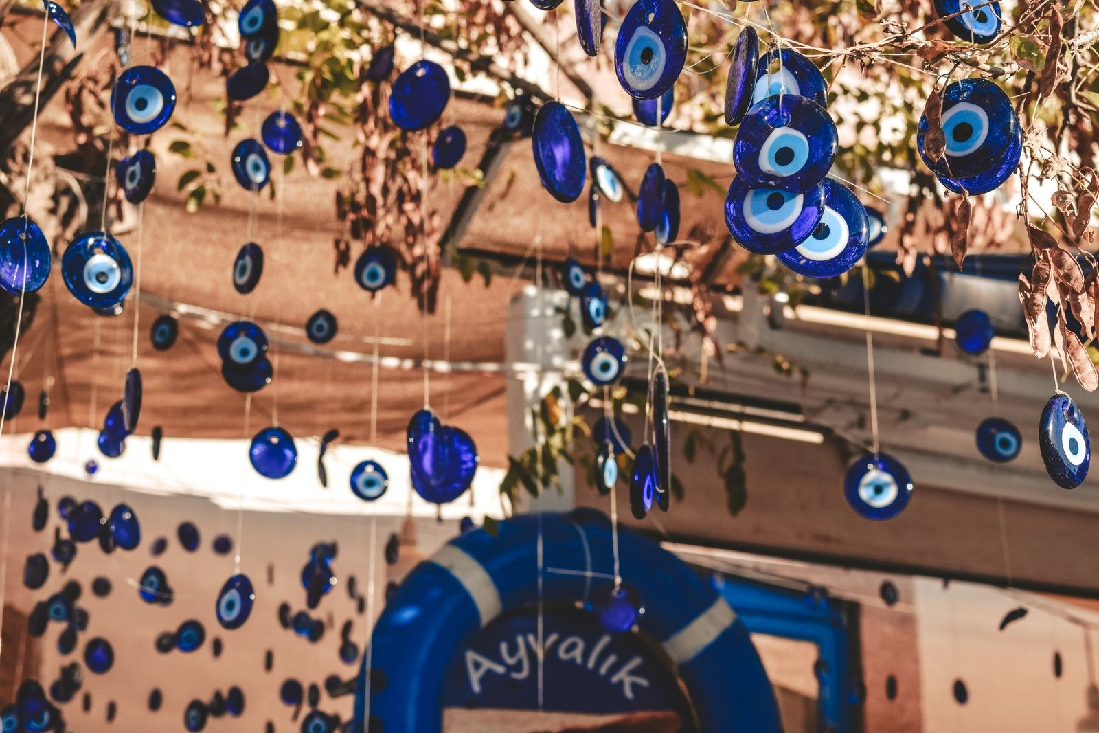 Blue glass Nazar amulets (evil eye beads) hanging from strings in a colorful street installation, creating a sea of blue circles.
